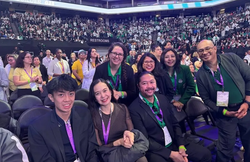 Team members seated together in a full convention arena