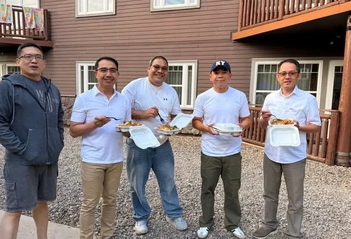 Five team members sharing lunch outside the lodge