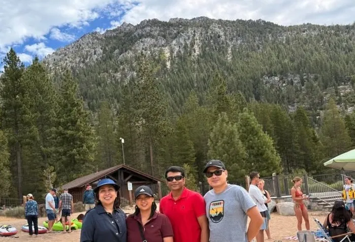 Four team members smiling in front of a forested mountain