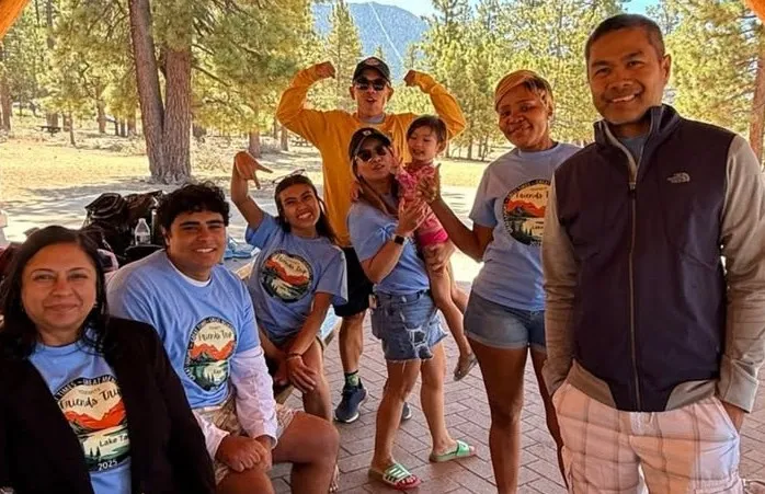 Team members and family at a picnic table under the pavilion