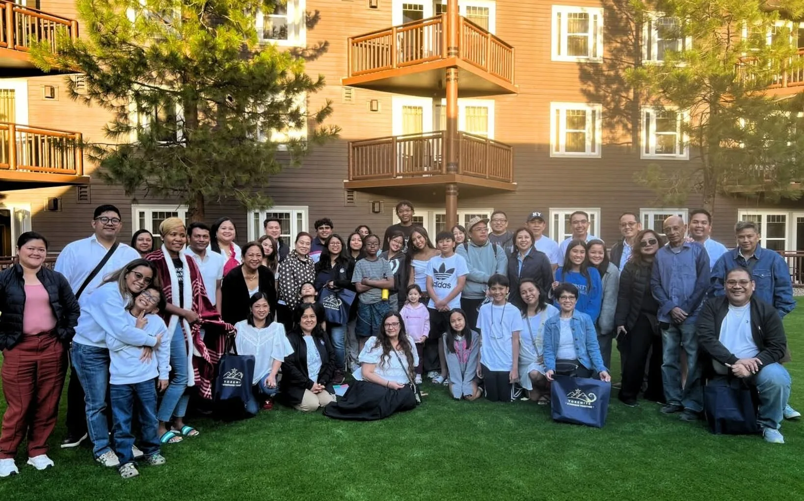 The Yosemite Gold team and their families gathered on a lawn outside a lodge